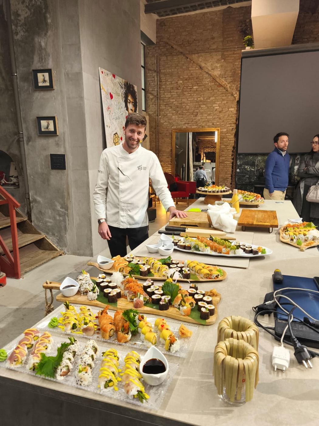 Chef sonriente junto a una mesa llena de sushi