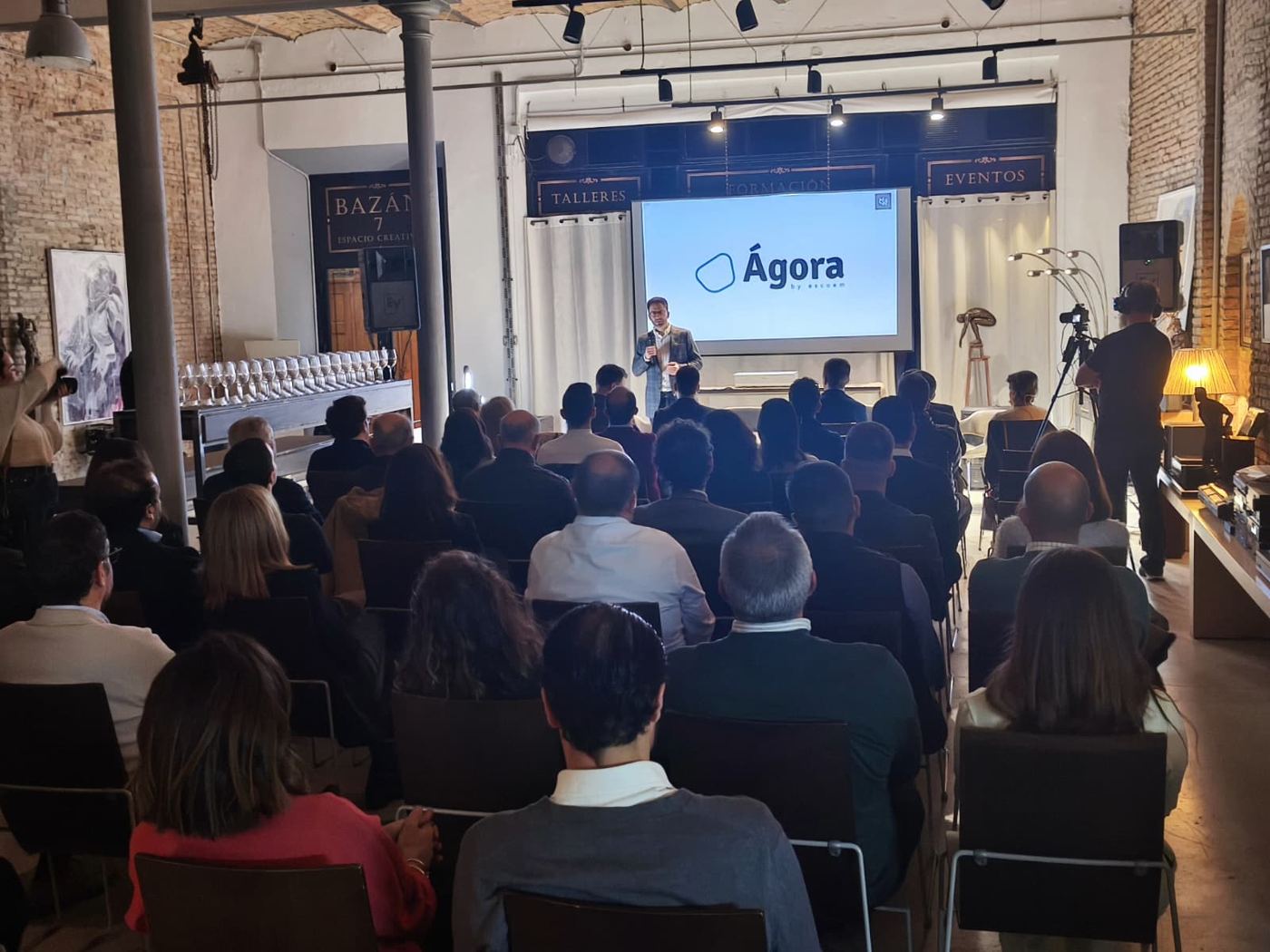 Presentación ante un público sentado en una sala de ladrillo visto